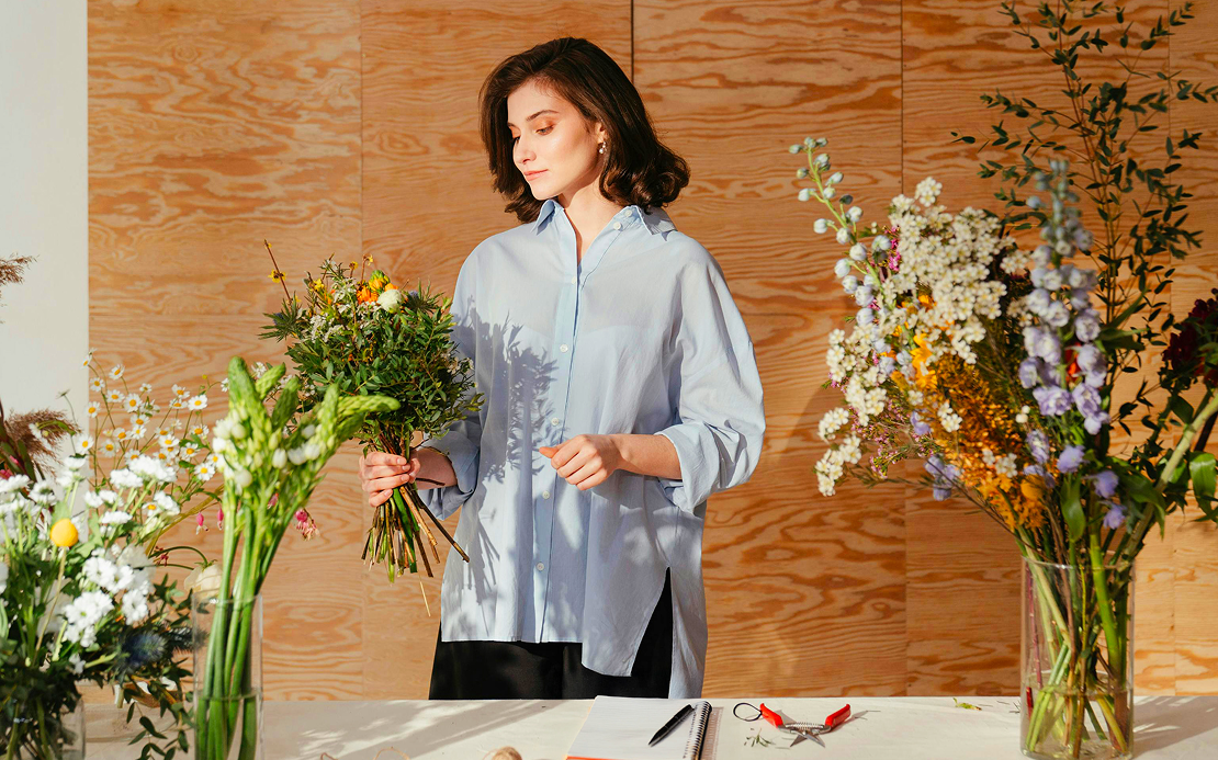 Donna con un mazzo di fiori in mano e sul tavolo
